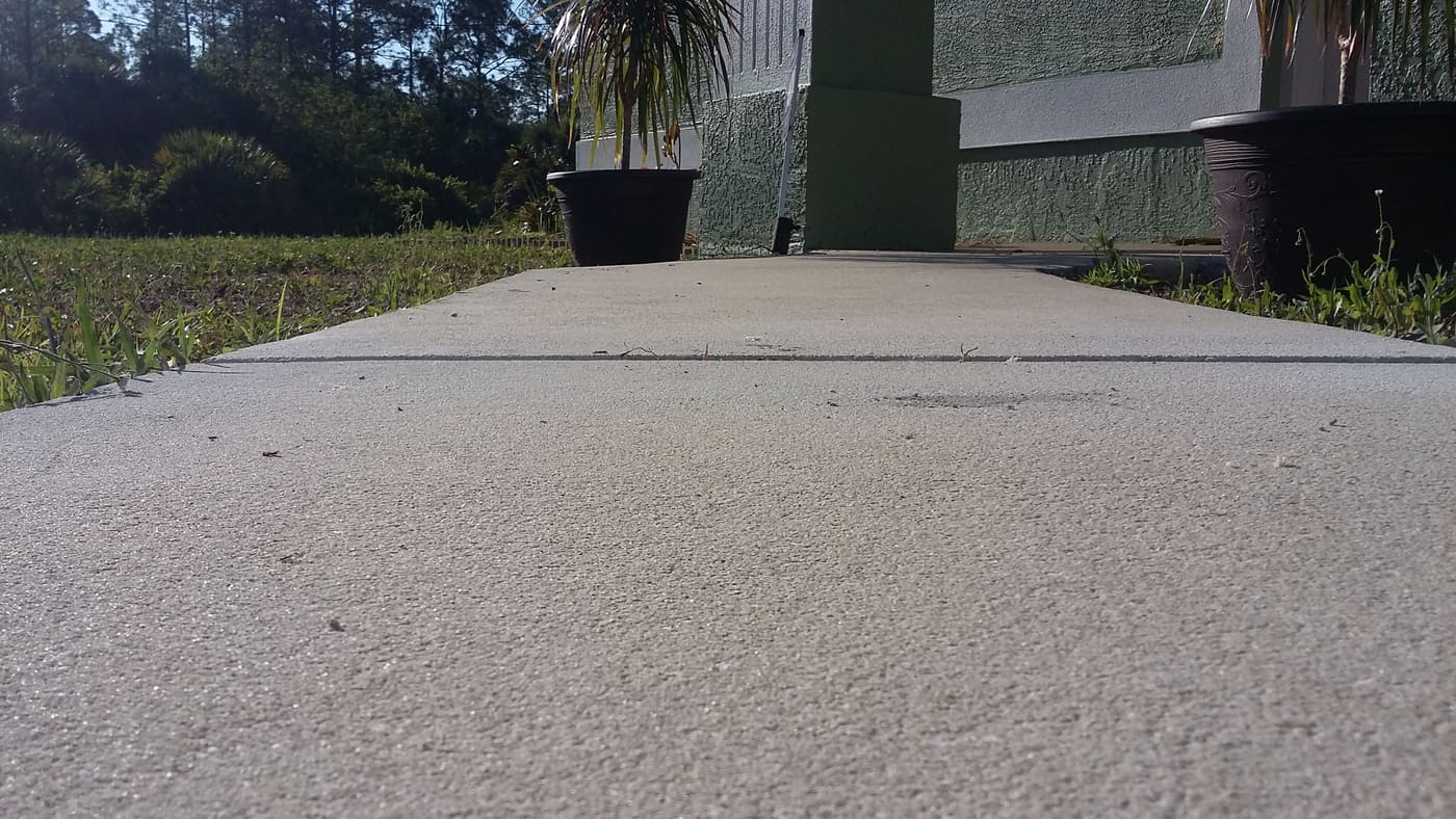 Uneven sidewalk slab settlement before foam lifting repair